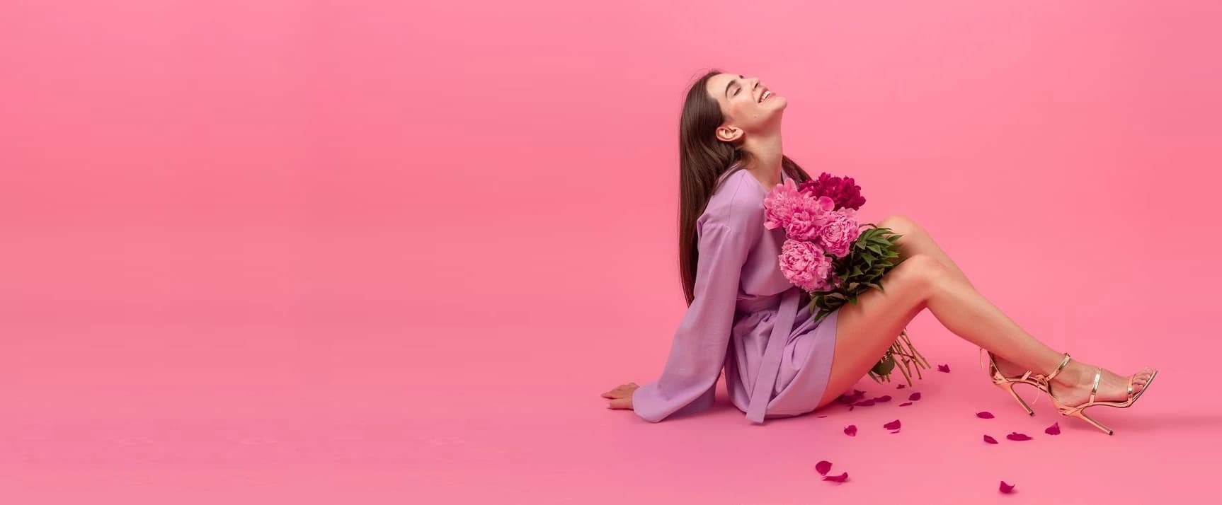 Woman holding a bouquet of pink peonies on a pink background